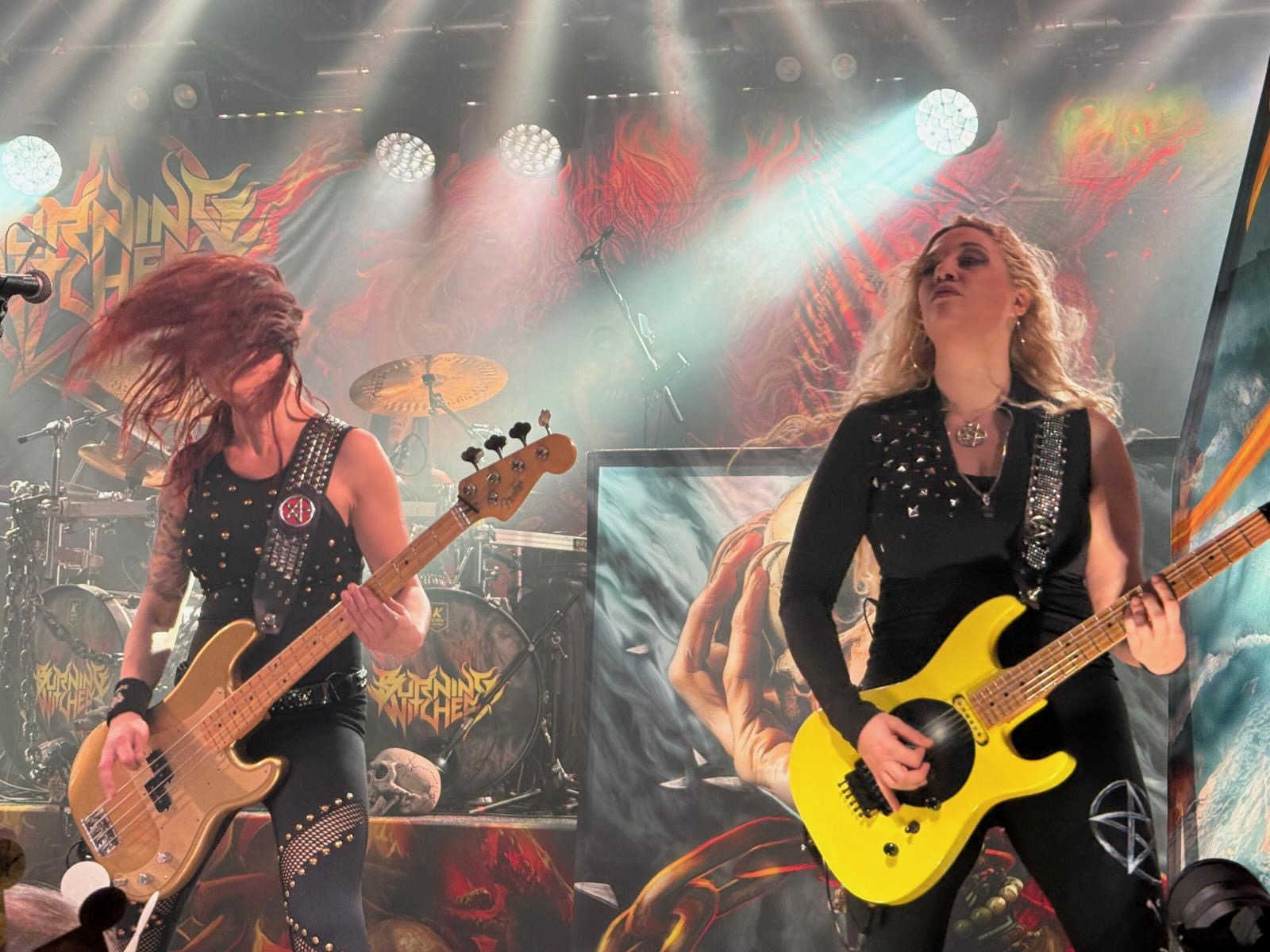 Auf dem Foto sieht man die Bassistin und die Gitarristin der Band Burning Witches mit ihren Instrumenten beim spielen